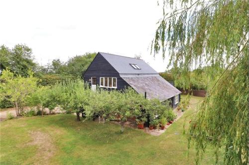a black house with a bunch of apple trees at Little Puddingcake - Adorable 1 bedroom guesthouse near Chapel Down in Rolvenden