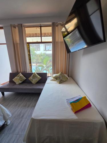 a room with a bed and a window and a couch at Posada Casa Bonita in Puerto Maldonado