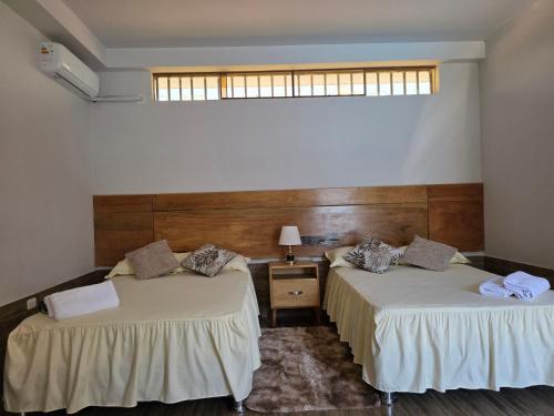 two beds in a room with a window at Posada Casa Bonita in Puerto Maldonado