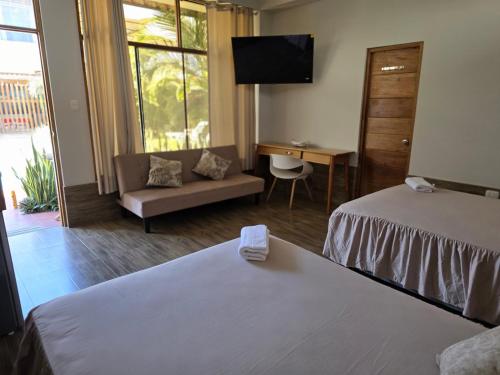 a room with two beds and a couch and a television at Posada Casa Bonita in Puerto Maldonado
