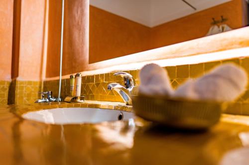 a bowl on a counter next to a bathroom sink at Riad Dar Dialkoum in Marrakech