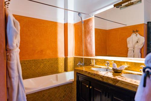 a bathroom with a sink and a tub and a mirror at Riad Dar Dialkoum in Marrakech