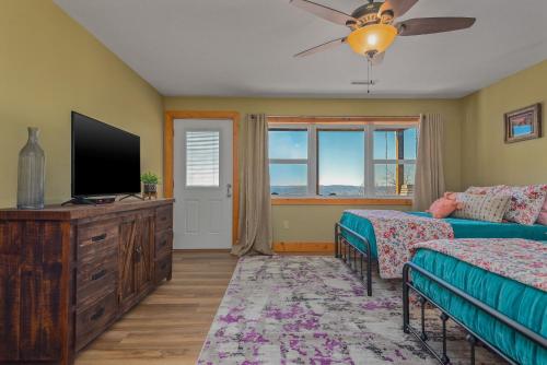 a bedroom with two beds and a flat screen tv at Ozark Retreat with Mountain Views Fire Pit & Deck in Parthenon