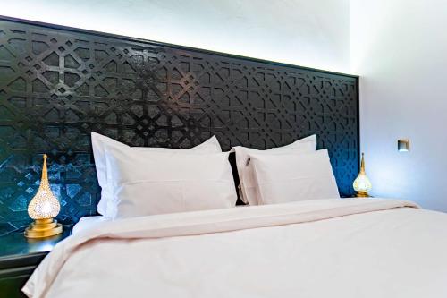 a bedroom with a large white bed with a black headboard at Riad Dar Dialkoum in Marrakech
