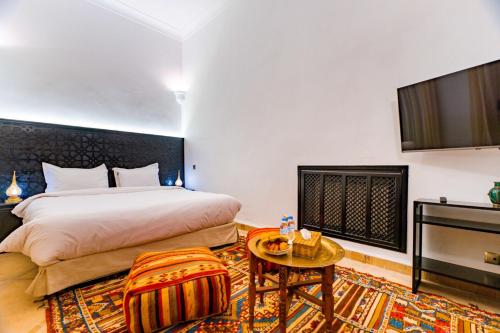 a hotel room with a bed and a tv at Riad Dar Dialkoum in Marrakech