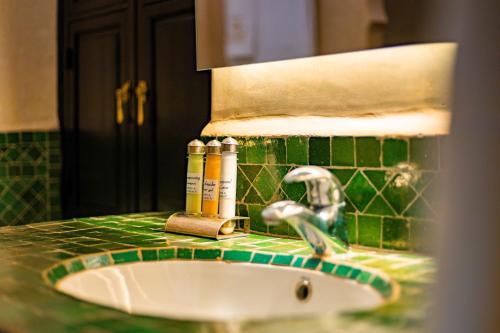 a bathroom sink with two bottles on a green tiled counter at Riad Dar Dialkoum in Marrakech
