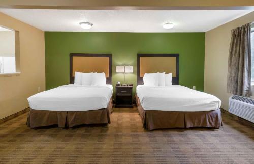 two beds in a hotel room with green walls at Extended Stay America Suites - Raleigh - North Raleigh - Wake Towne Dr in Raleigh