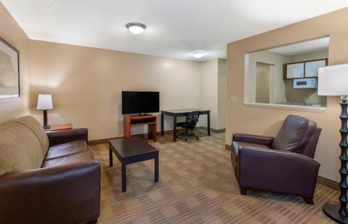 a living room with a couch and a tv and a table at Extended Stay America Suites - Raleigh - North Raleigh - Wake Towne Dr in Raleigh