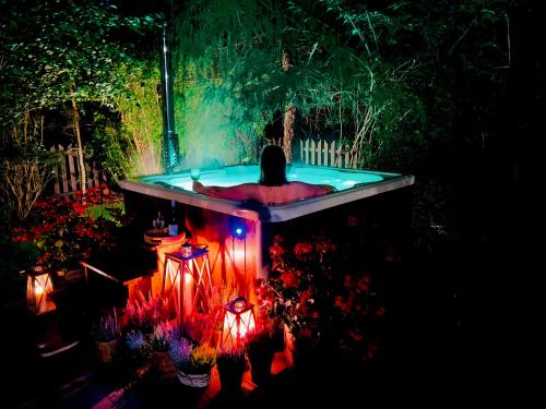 a person in a hot tub with lights in a garden at Dom Marzeń z jacuzzi pod gwiazdami in Kopalino