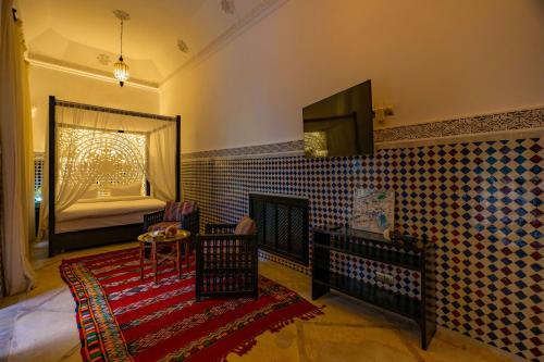a living room with a fireplace and a tv on the wall at Riad Dar Dialkoum in Marrakech