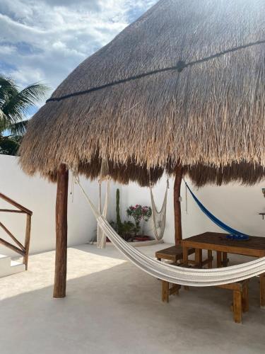 a hammock with a thatched umbrella and a table at Casa Loto D in Chelem
