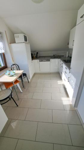 a kitchen with white cabinets and a table and a floor at Familie Pöllet in Stammham
