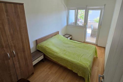 a small bedroom with a green bed and a window at Apartments with parking space Seget Vranjica, Trogir - 24874 in Seget Vranjica