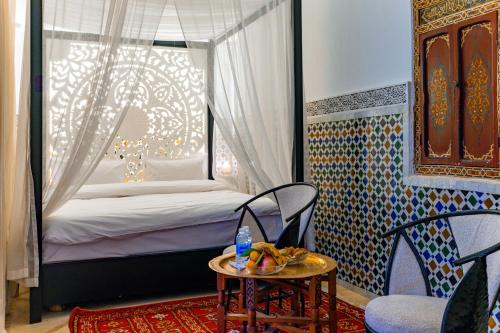 a room with a bed and a table and chairs at Riad Dar Dialkoum in Marrakech