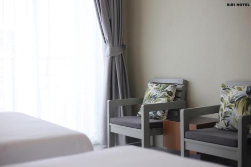 a bedroom with two chairs and a bed and a window at Siri Hotel Phuket in Phuket Town