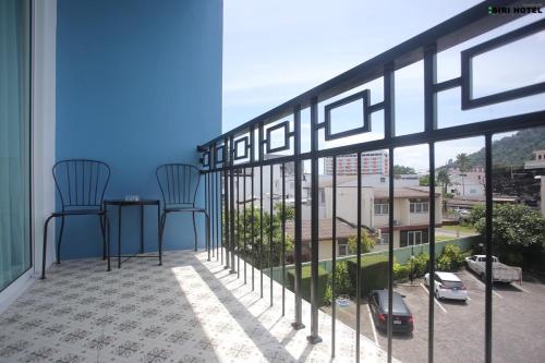 a balcony with two chairs and a view of a city at Siri Hotel Phuket in Phuket Town