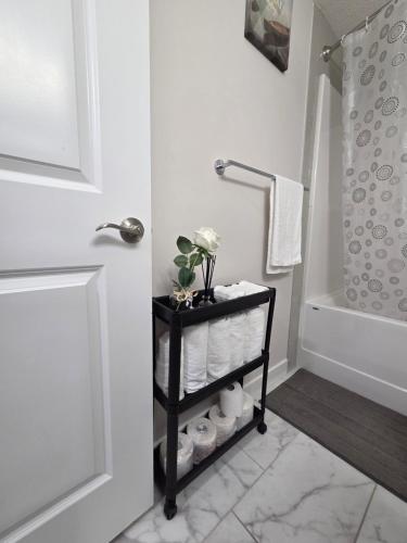 a bathroom with a black cart with towels and a shower at Little Heaven 2BR southwest Calgary in Calgary