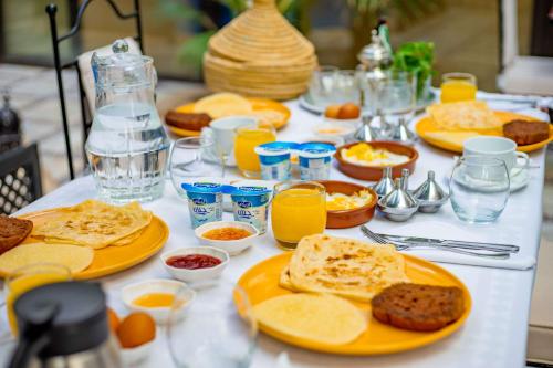 a table with plates of food and glasses of orange juice at Riad Dar Dialkoum in Marrakech