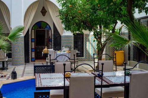 a courtyard with tables and chairs and a pool at Riad Dar Dialkoum in Marrakech