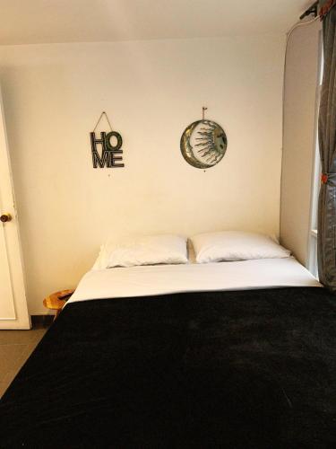 Un dormitorio con una cama y un reloj en la pared. en Amplio, Cómodo y tranquilo Apto cerca a Milan y Cable Plaza, en Manizales