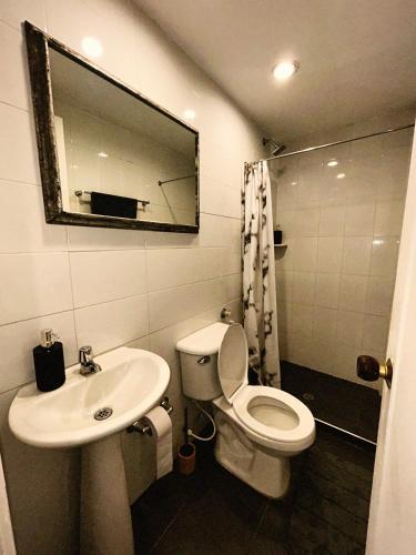 Un baño con inodoro, lavabo y espejo. en Amplio, Cómodo y tranquilo Apto cerca a Milan y Cable Plaza, en Manizales