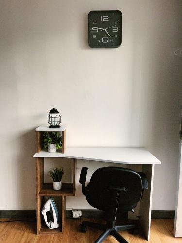 a desk with a chair and a clock on the wall at Aparta Estudio Confortable, Lujoso y Comodo en Milan in Manizales