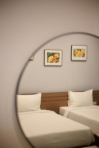 two beds in a room with two framed pictures on the wall at Siri Hotel Phuket in Phuket Town