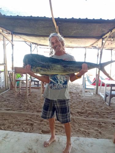 a man standing on the beach holding a surfboard at My Beach House - Lombok - Kuta - Areguling beach in Kuta Lombok