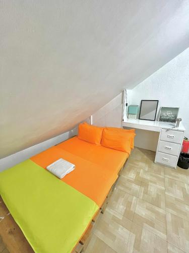 a bedroom with a bed with an orange and yellow blanket at Nomads MNL Backpackers Homestay - near Airport in Manila