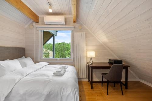 a bedroom with a bed and a desk and a window at Gekko Hanazono in Kutchan