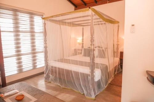 a bedroom with a canopy bed in a room at Beach Club Bungalow Induruwa in Induruwa