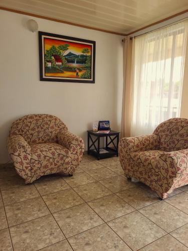 a living room with two chairs and a table at Arenal Dreams Apartments in Fortuna
