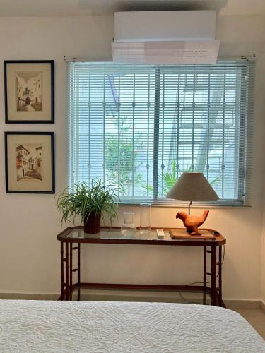 a bedroom with a table with a lamp and a window at Fun House Tampiquito in Monterrey