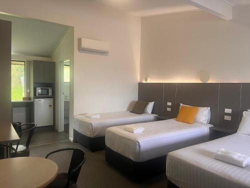 una habitación de hotel con dos camas y una mesa en Fern Bay Motel, en Newcastle