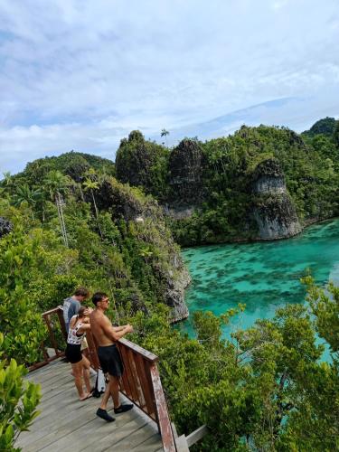 a group of people standing on a boardwalk near the water at Mares Homestay-Raja Ampat in Fam
