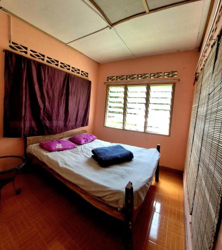 a bedroom with a bed with pink pillows and a window at Devalley Basecamp in Kampong Ulu Dong
