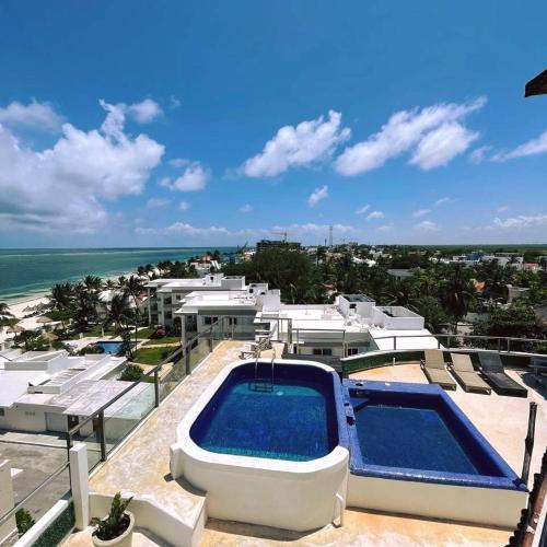 a swimming pool on top of a resort with the ocean at MoonLight Condos in Puerto Morelos