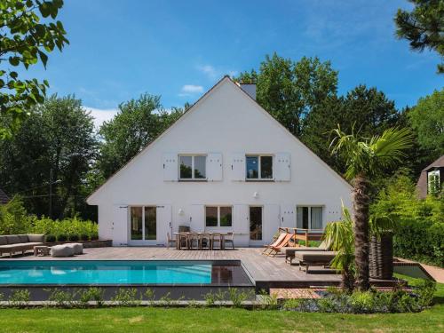 a white house with a swimming pool in front of it at Charmante Villa avec Piscine et Animaux Admis au Cœur du Touquet - FR-1-821-46 in Le Touquet-Paris-Plage