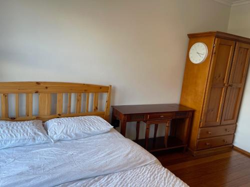 a bedroom with a bed and a dresser and a clock at Home in Laverton 19 Minutes to Melbourne CBD in Laverton