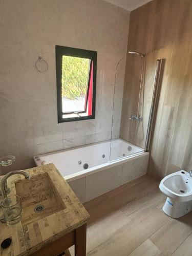 a bathroom with a tub and a toilet and a sink at Complejos Del Jaguel house in Santa Teresita