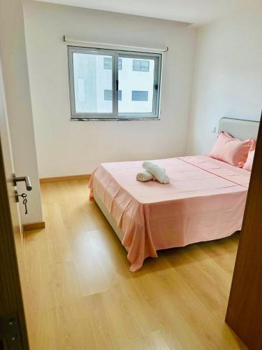 a bedroom with a bed with pink sheets and a window at Levy-Cardoso Apartment in Praia
