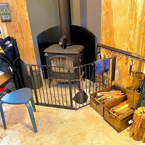 a wood stove in a room with a chair at SNUG CAMP HOUSE in Okubo