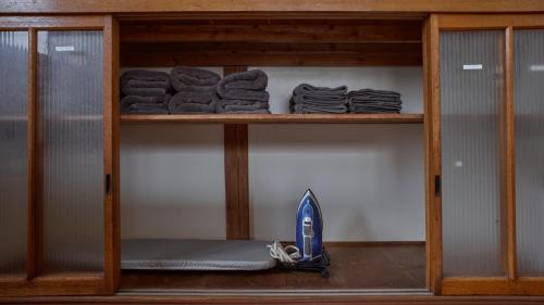 a shelf with folded towels and a vacuum on it at Five Peaks Yudanaka in Yamanouchi