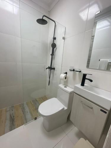 a white bathroom with a toilet and a sink at Mar, Sol y Arena in Paraíso