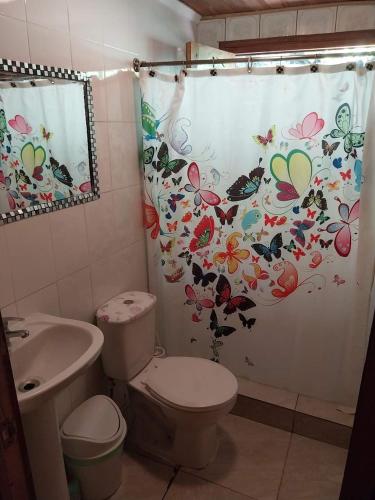 a bathroom with a toilet and a shower curtain with butterflies at CasaLagoRapel in El Estero