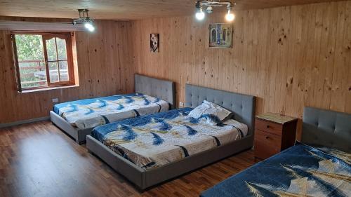 two beds in a room with wooden walls at CasaLagoRapel in El Estero