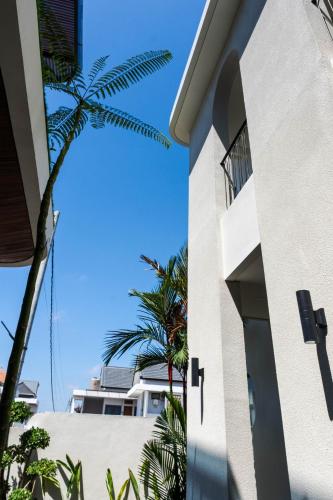 a white building with a palm tree next to it at Sascanaluna Padma Bali in Kesiman