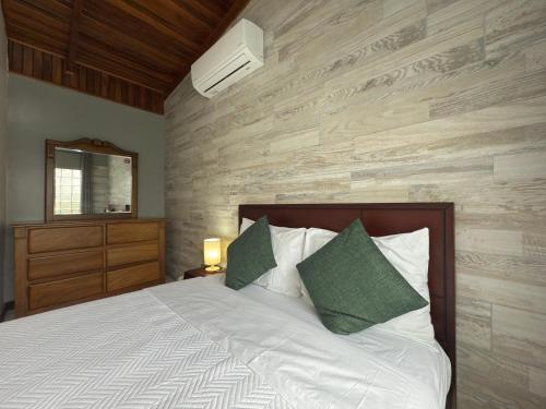 a bedroom with a bed with white sheets and green pillows at Stada San Jose Airport Hotel in Alajuela City