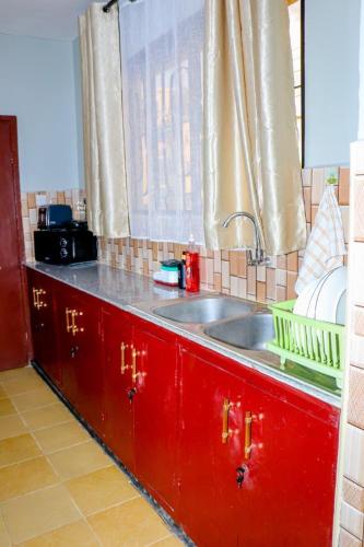 a kitchen with red cabinets and a sink and a window at NT Homes in Dar es Salaam