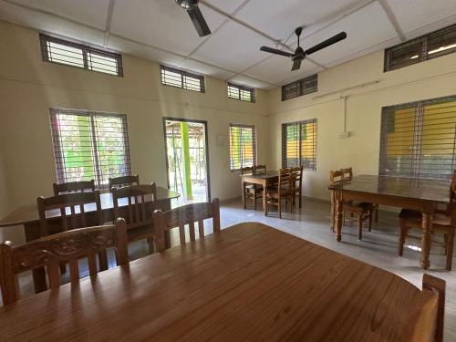 a dining room with tables and chairs and windows at New Kaziranga Cottage in Kāziranga